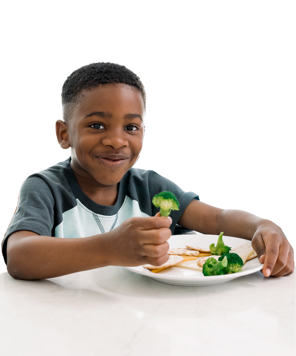 boy eating broccoli, smiling