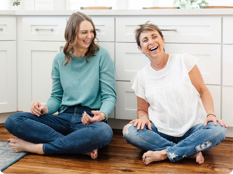 two women sitting on the floor laughing